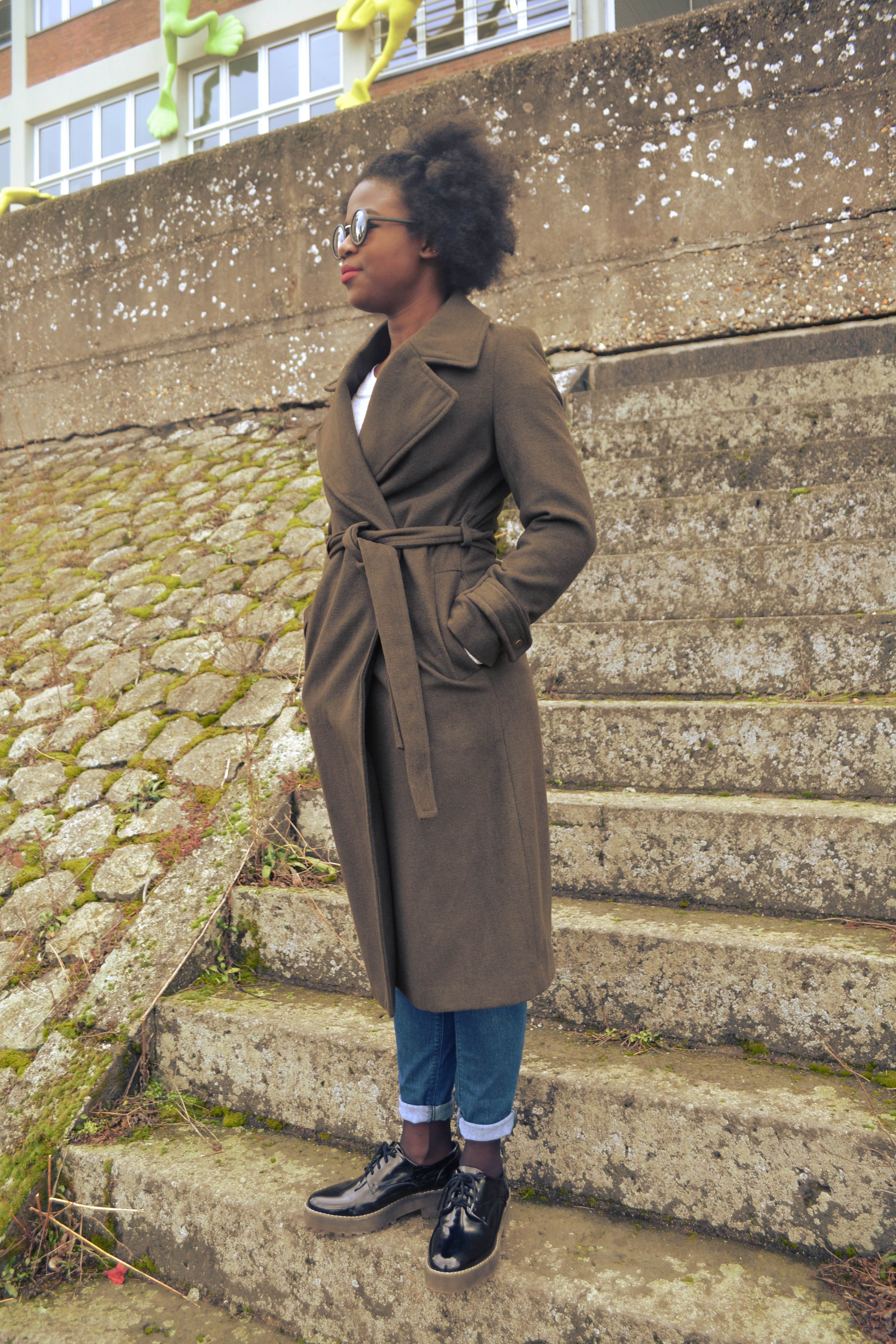 A woman is standing on outdoor steps with her hands in coat pockets